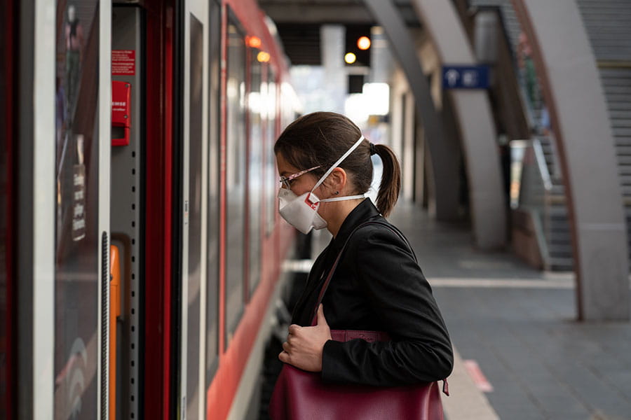 Frau trägt FFP3-Maske beim Einsteigen in den Zug.